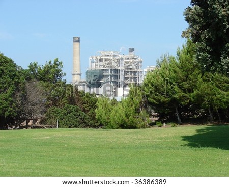 beautiful green park with industrial factory and smokestack in background