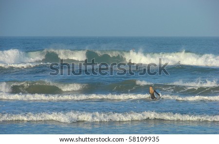 female surfer heading out to ocean to find waves