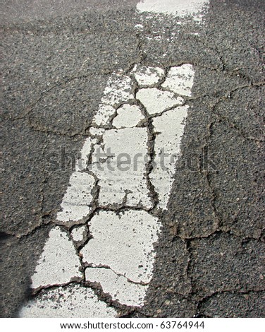 extremely weathered and cracked crosswalk on pavement