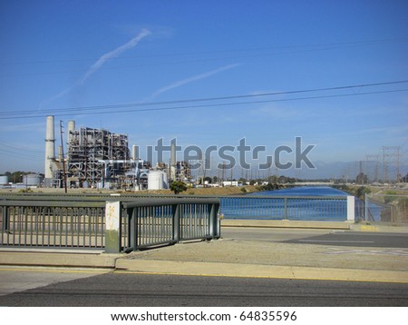 industrial factory along river with smokestacks spewing pollution