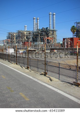 industrial factory with smokestacks behind security fence