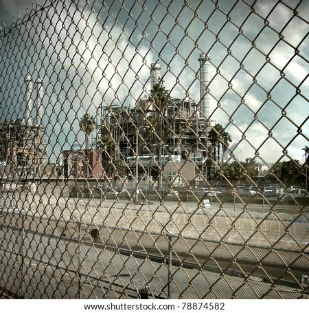 aged and worn vintage photo  of industrial factory behind fence