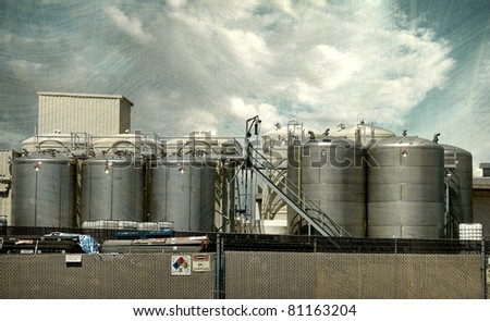 aged vintage photo of chemical silos with warning labels