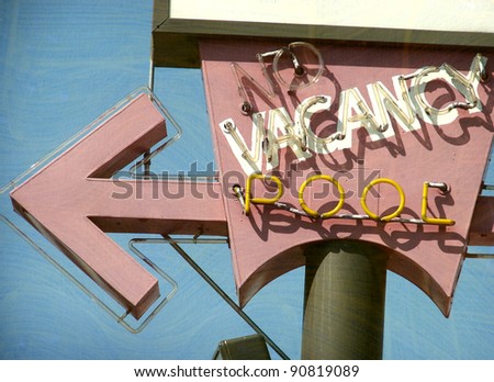 aged and worn vintage photo of neon motel no vacancy and pool sign