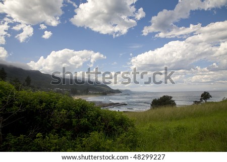 a rugged coastline on the new south wales south coast, with clouds shrouding the mountain tops