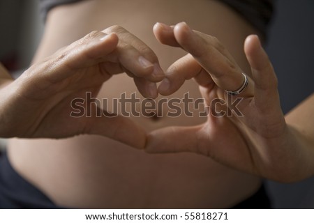 stock photo : love heart being made by a pregnant mother over her tummy with 