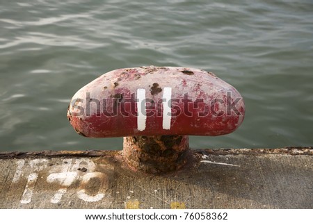 a red ship bollard on the dockside with the number 11 painted on it