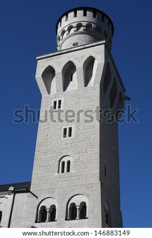 Medieval castle turret against clear blue sky, immaculate masonry, strong shadow lines