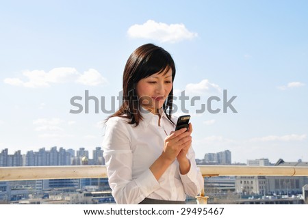businesswoman smiling while looking on the mobile phone, outside, space for copy