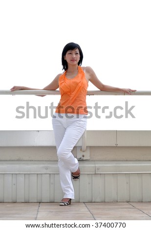 woman in orange blouse standing on a balcony, white background