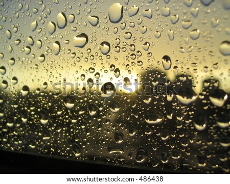 rain drops on the window, sunset in background, stormy clouds behind