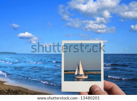 hand holding a holiday photo, beautiful seashore in background, photo inside is my property