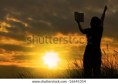 female praying with bible against summer sunset