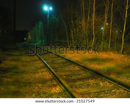 Railway / railroad tracks leading into the black tunnel - Shadow and light