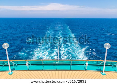 The stern of a ship with the trail in the sea in the background