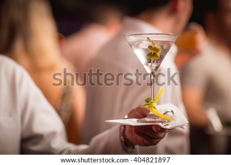 A waiter holding a dry martini in a classic glass