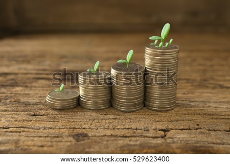 stack of coins with small green plant on wooden table,concept idea for save and growth and business