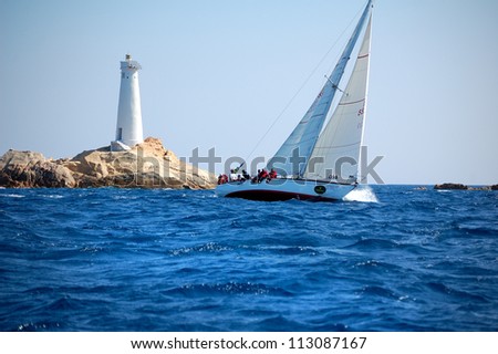 PORTO CERVO, ITALY - SEPTEMBER 12:  Sailing team in front of Monaci Lighthouse compete in the  Rolex Swan Cup boat race on September 12, 2012 in Porto Cervo, Italy.