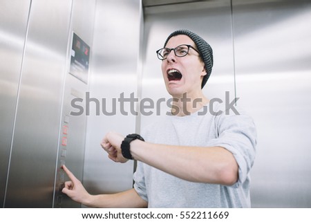Young stylish guy standing in elevator and sreaming in a despair, because he realised he had missed one of the most important moments in his life. He is crying