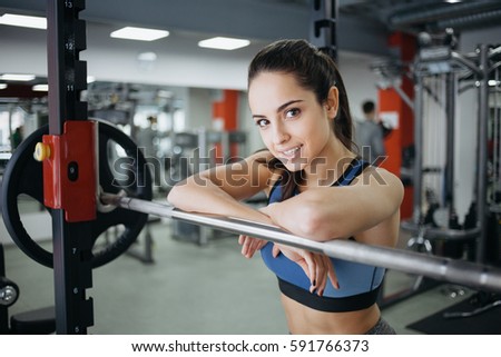 Young woman with ponytail at the gym using fitness equipment. Satisfied girl enjoying her training. She is relaxing hanging upon the bar. Close up. View from the right side