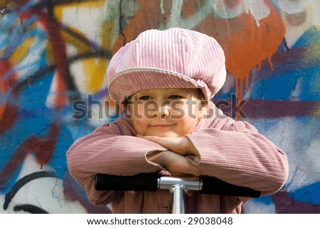 Portrait of happy little girl who is taking a respite near graffiti painted wall