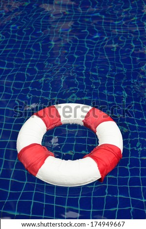 red and white life buoy floating in the blue background swimming pool