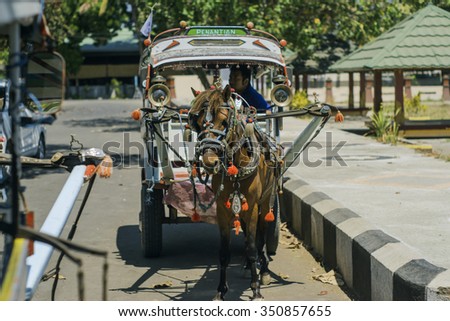 BANGSAL FERRY TERMINAL, INDONESIA - SEPTEMBER 6, 2015 : An unidentified man with horse carriage looks for customers. Horse carriage are still used for transportation in Lombok, Indonesia.