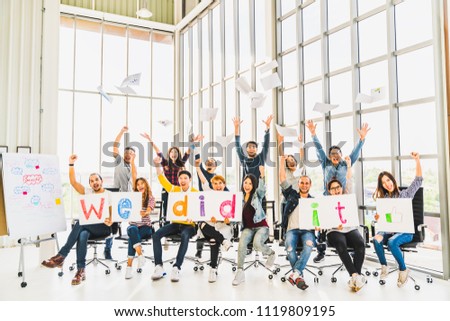 Multiethnic diverse group of happy business people cheering together, celebrate project success with papers wrote words We did it. Coworkers teamwork, career job achievement, or small business concept
