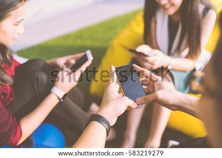Group of three young people using smartphones together, modern lifestyle or communication technology gadget concept, depth of field effect