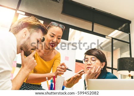 Multiethnic diverse group of creative team, casual business people, or college students in strategic meeting or project brainstorm discussion at office, using smartphone. Startup or teamwork concept.