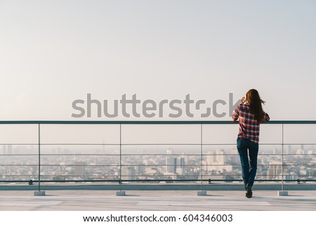 Woman using mobile phone at rooftop during sunset with copy space, communication or lonely people concept.