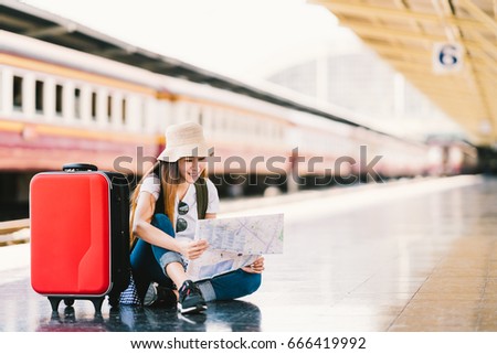 Asian backpack traveler woman using generic local map, siting alone at train station platform with luggage. Summer holiday traveling or young tourist concept