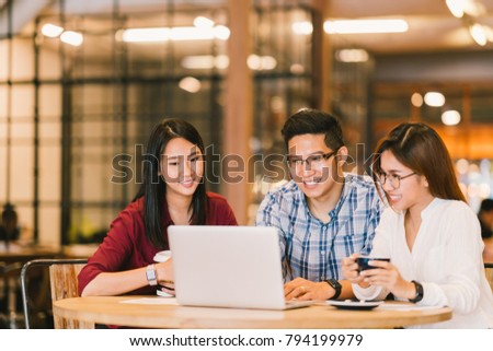 Young Asian college students group or coworkers using laptop computer together at cafe or university. Casual business, freelance work, coffee break meeting, e-learning or e-commerce activity concept