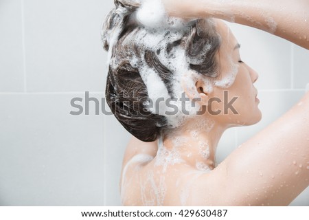 Woman in shower washing hair with shampoo.