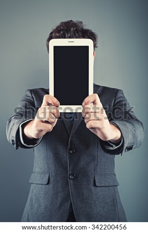 Businessman holding digital tablet in front of his face