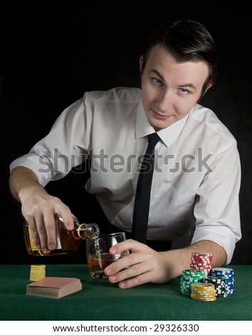 Young bartender pouring whiskey at the casino table with deck of cards and chips