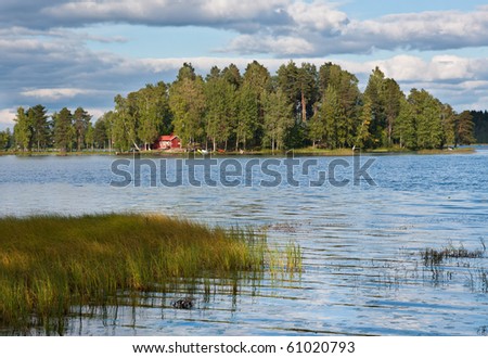 Island on lake in Finland with red summer cottage
