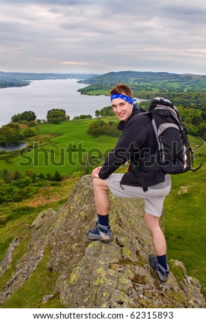 Happy young man on the rock above the lake in Lake District, UK