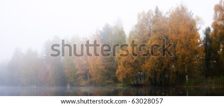 Misty morning on lake in Finland with beautiful colored trees in Autumn
