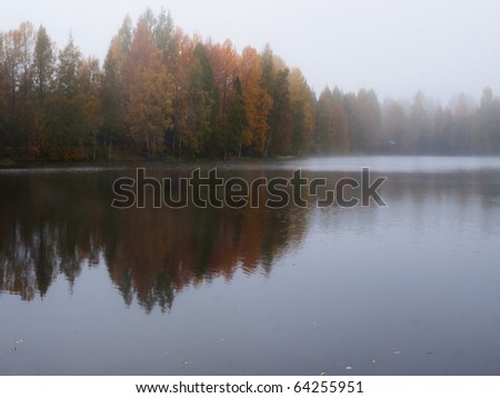 Misty morning on lake in Finland with beautiful colored trees in Autumn