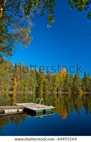 Jetty from sauna to lake with beutiful colors on autumn and reflection of trees in Finland.