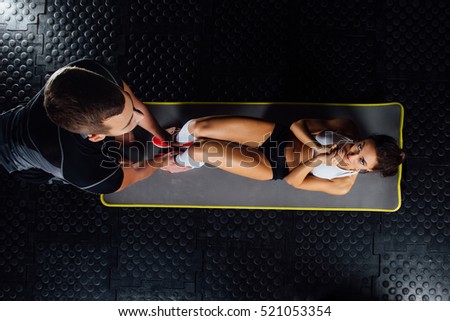 Woman doing abdominal crunches press exercise on the mat with her sports male trainer in gym concept sport, fitness, lifestyle and people. Couple exercises.