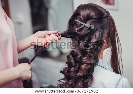 Closeup hairdresser coiffeur makes hairstyle.