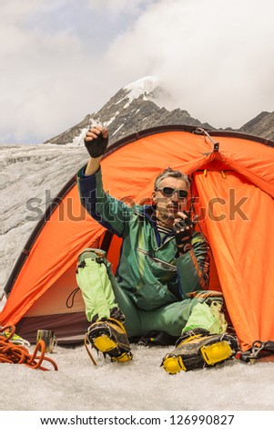 The climber sits in tent and causes the help highly in mountains