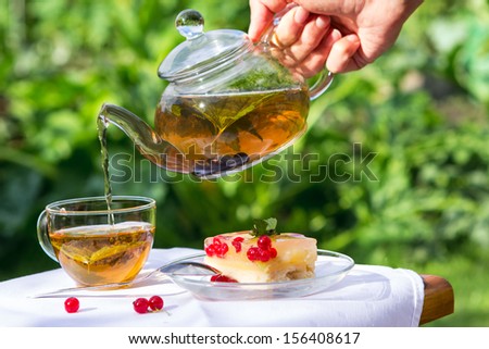 To pour tea in a glass and pie on table in garden
