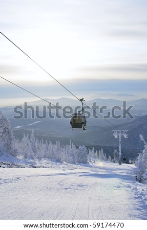 Cabin lift of skiers and snowboarders  on background mountain landscape
