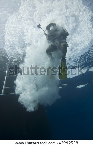 One Scuba diver entering the water from a dive boat. Red Sea, Egypt.