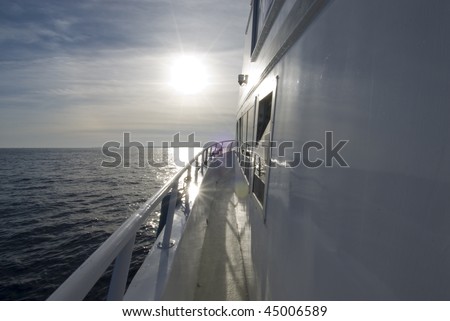 Side view of a white boat heading into the sun on a calm sea. Red Sea, Egypt.