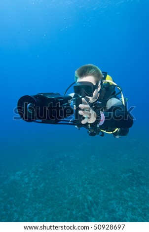 Front view of an Underwater camerman filming in crystal clear water. MORE INFO: Model released