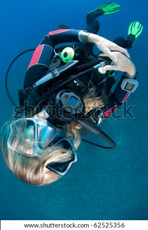 One female scuba diver swimming on her back with hair obscuring her face.